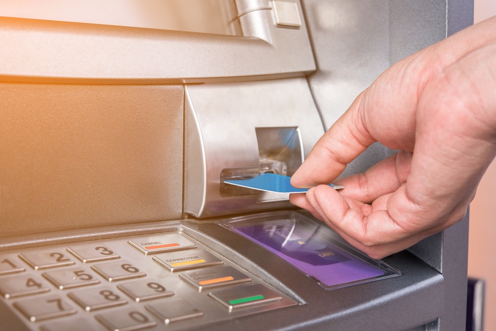 hand inserting a bank card into an ATM machine
