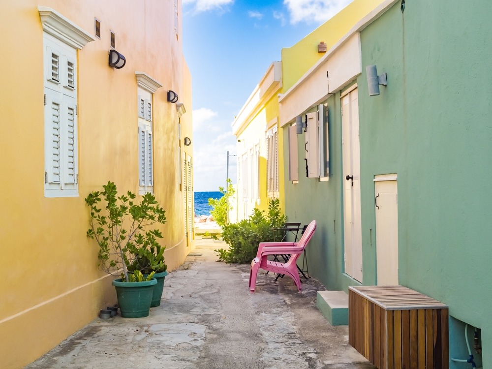 Alley between colorful Caribbean houses with in the background the sea